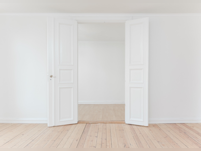 An empty bedroom with white French doors.