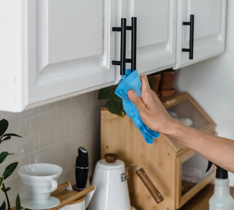 Cleaner deep cleaning a white kitchen cabinet.